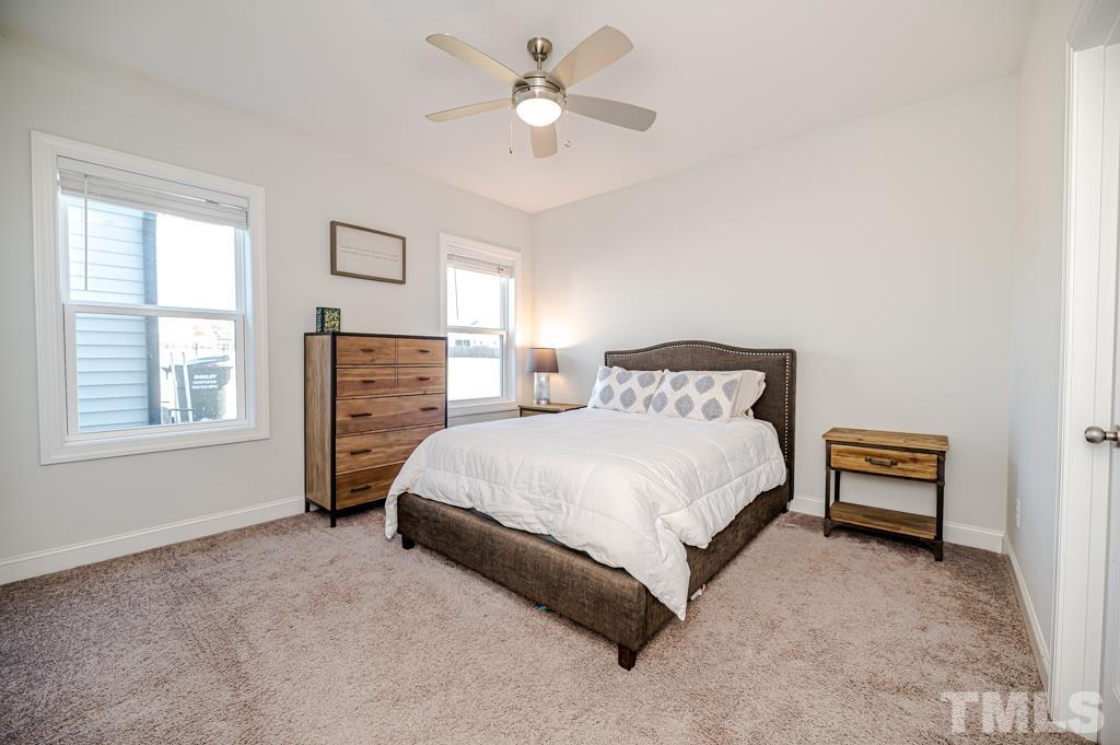 6712 Lucado Court Raleigh, NC 27603 - Photo 30 of 52 a spacious bedroom with a bed and a chandelier