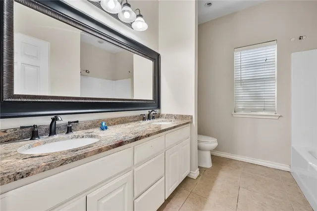 a bathroom with a granite countertop toilet sink and mirror