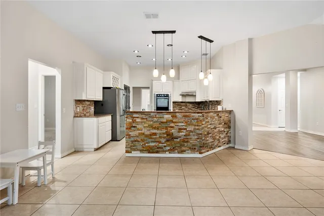 a kitchen with stainless steel appliances kitchen island granite countertop a stove a refrigerator a sink a oven and a refrigerator