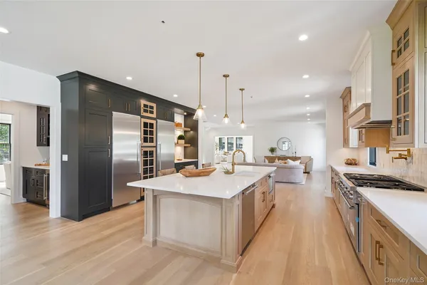 a large kitchen with stainless steel appliances a stove a sink dishwasher and a refrigerator with wooden floor