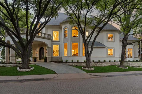 a front view of a house with garden and trees