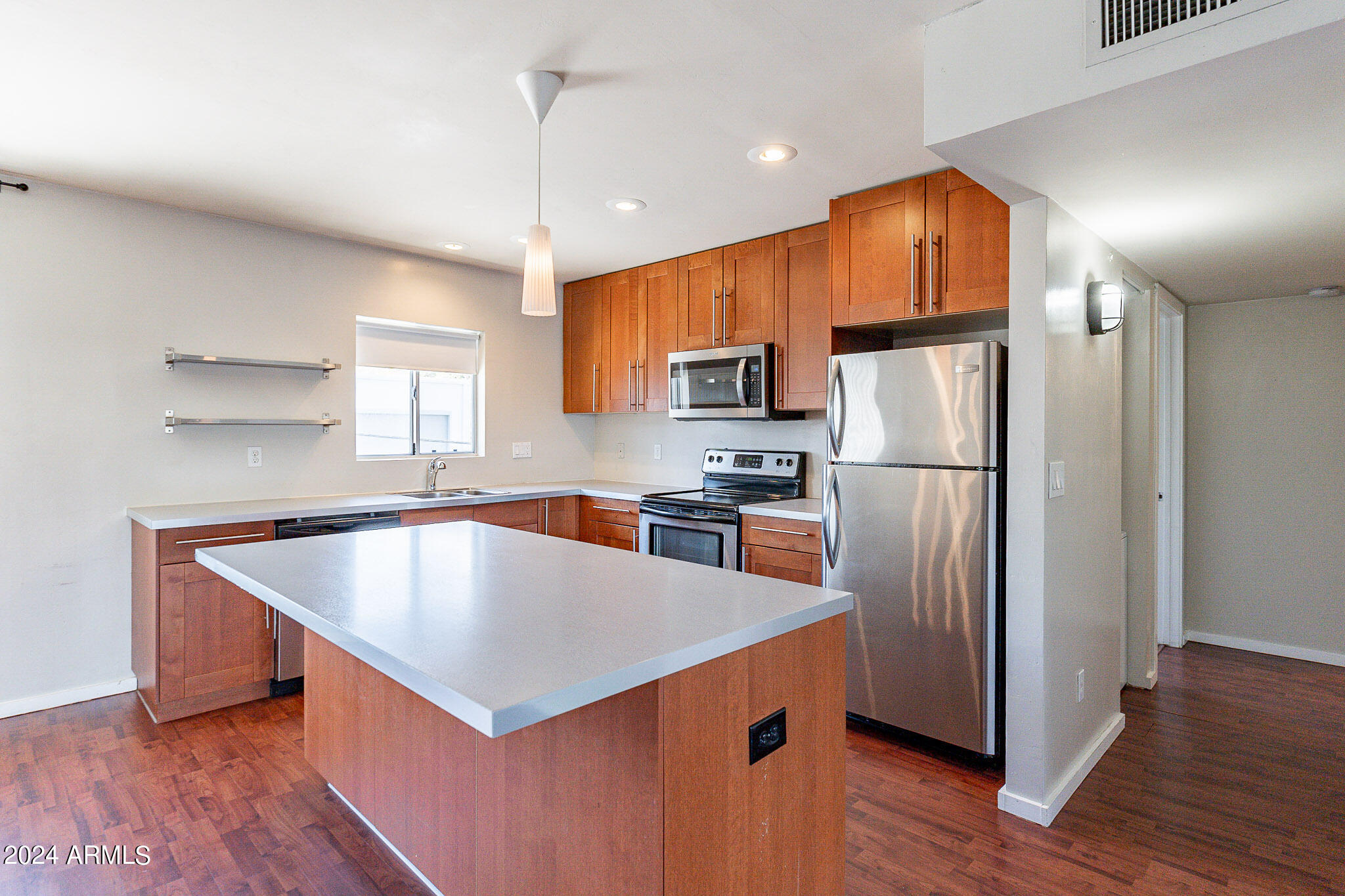 1630 East Georgia Avenue, Unit 204 Phoenix, AZ 85016 - Photo 5 of 23 a kitchen with kitchen island a refrigerator a sink dishwasher a stove with wooden floor and cabinets
