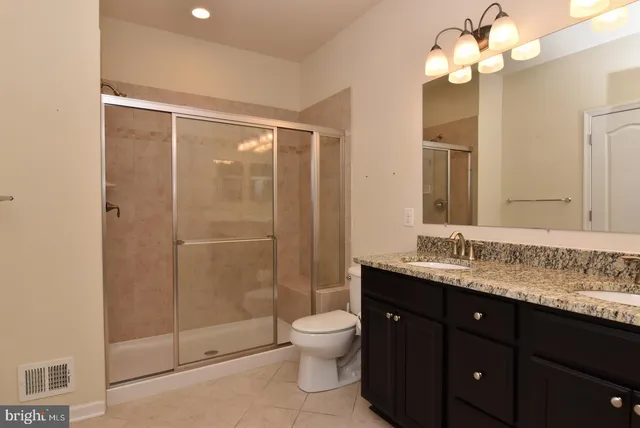 a bathroom with a granite countertop shower sink mirror and toilet