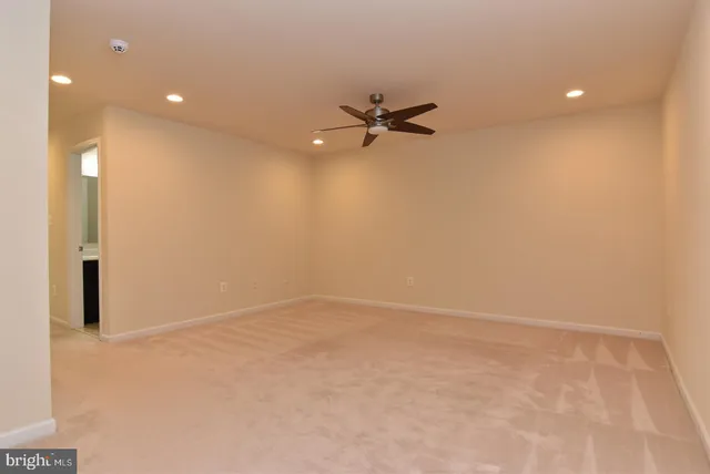 an empty room with a ceiling fan and carpet
