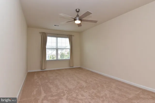 an empty room with ceiling fan and window
