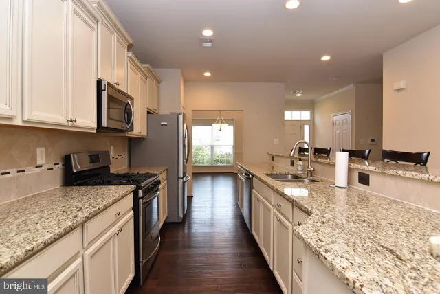 a kitchen with stainless steel appliances granite countertop a stove a sink and a wooden floors
