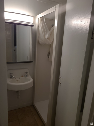 684 East 400 North Logan, UT 84321 - Photo 17 of 27 Compact bathroom featuring a wall-mounted sink with dual chrome faucets, a built-in shower stall, overhead vanity lighting, and tile flooring