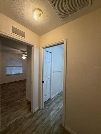 an empty room with wooden floor and fan
