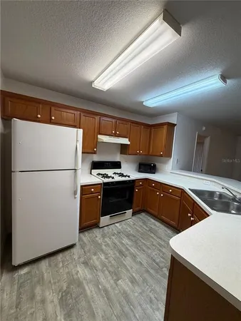 a kitchen with stainless steel appliances granite countertop a refrigerator a sink and a stove