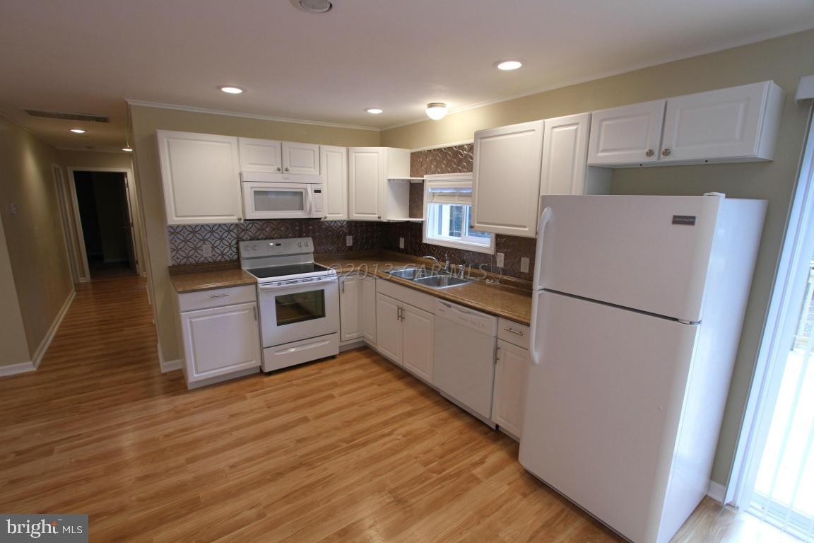 68 Sandyhook Road Ocean Pines, MD 21811 - Photo 11 of 35 a kitchen with a refrigerator a stove top oven and white cabinets