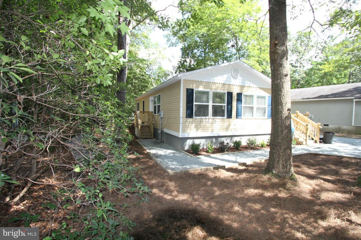 68 Sandyhook Road Ocean Pines, MD 21811 - Photo 22 of 35 a view of a small white house with large trees and outdoor space
