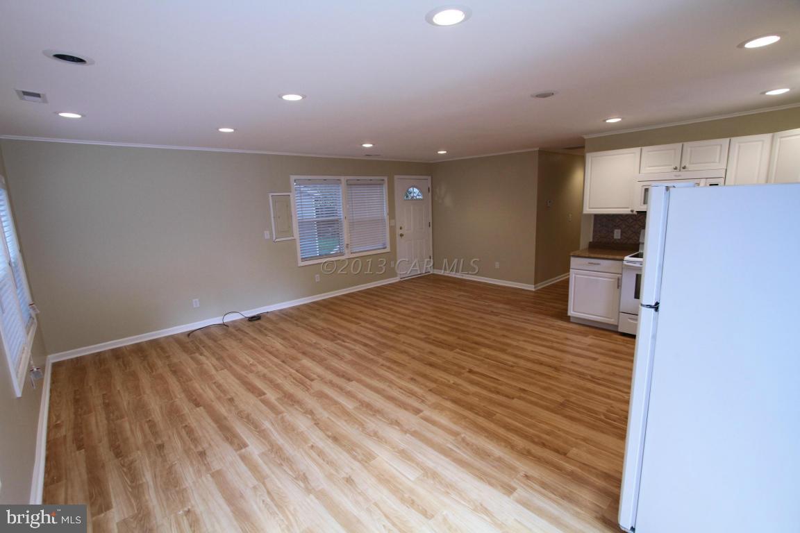 68 Sandyhook Road Ocean Pines, MD 21811 - Photo 5 of 35 an empty room with wooden floor and a kitchen