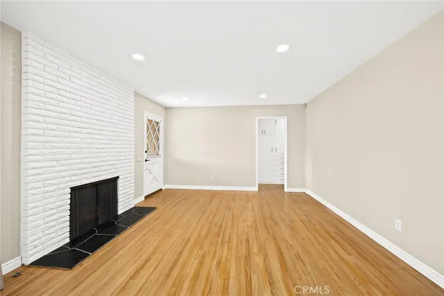 a view of empty room with wooden floor and fireplace