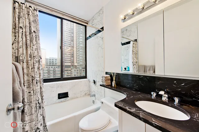 a bathroom with a granite countertop sink toilet a mirror and shower