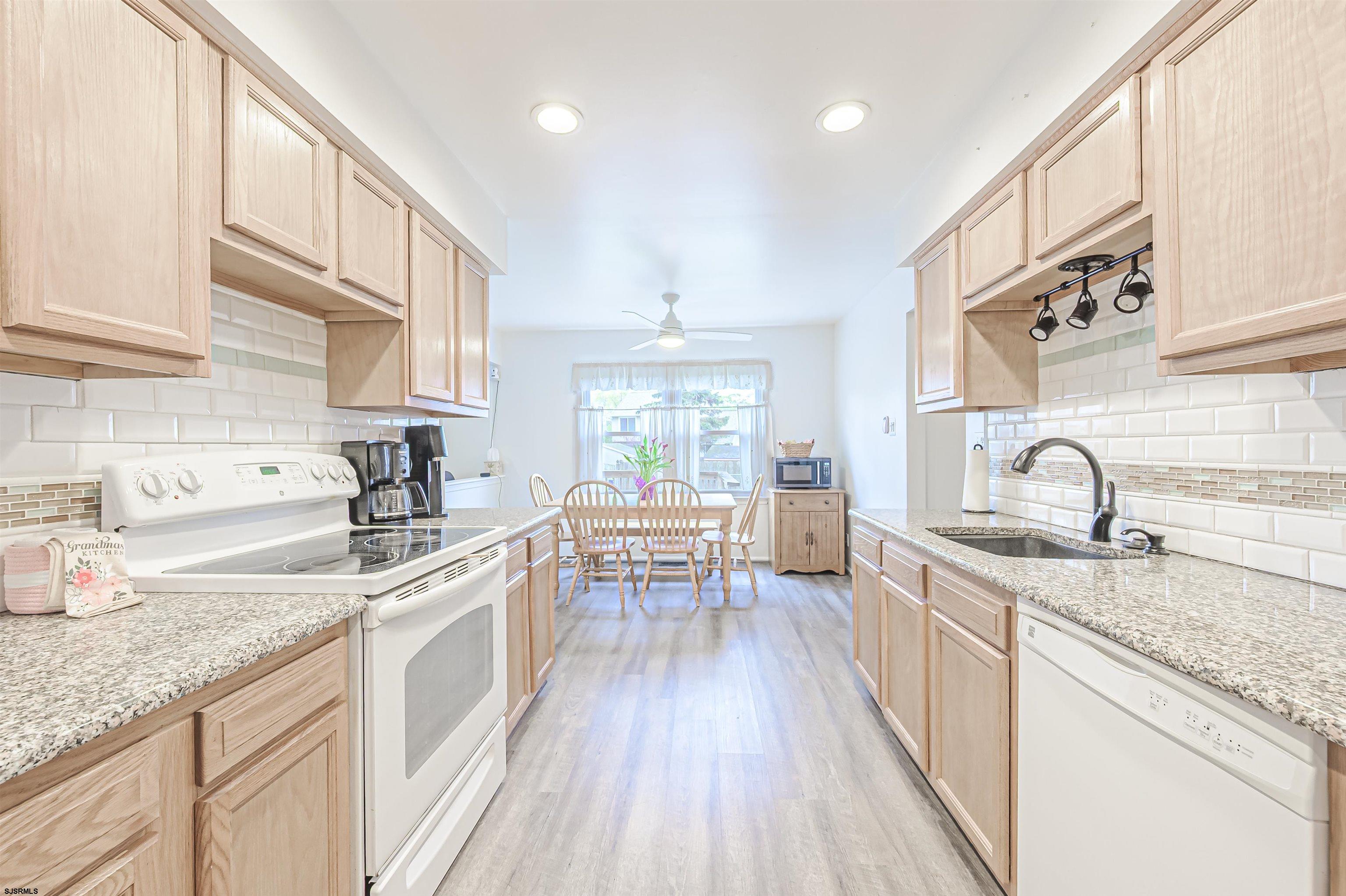 9 Rook Court Egg Harbor Township, NJ 08234 - Photo 8 of 27 a kitchen with granite countertop a sink dishwasher stove and white cabinets with wooden floor