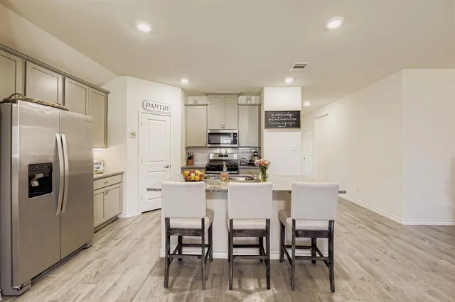 a kitchen with stainless steel appliances granite countertop a stove a sink a microwave a dining table and chairs with wooden floor