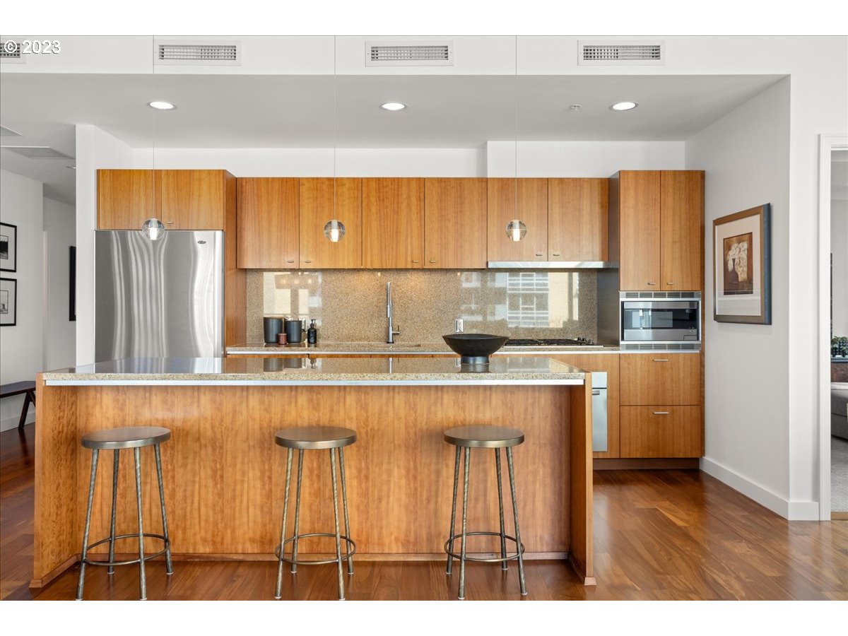 841 Southwest Gaines Street, Unit 1800 Portland, OR 97239 - Photo 17 of 39 a kitchen with kitchen island a counter top space a sink stainless steel appliances and cabinets