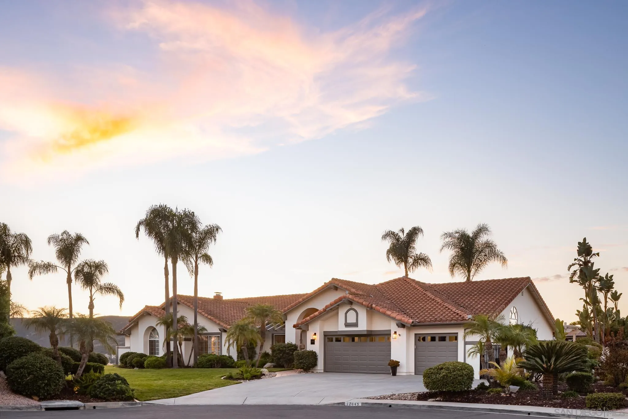 a front view of a house with a garden and trees
