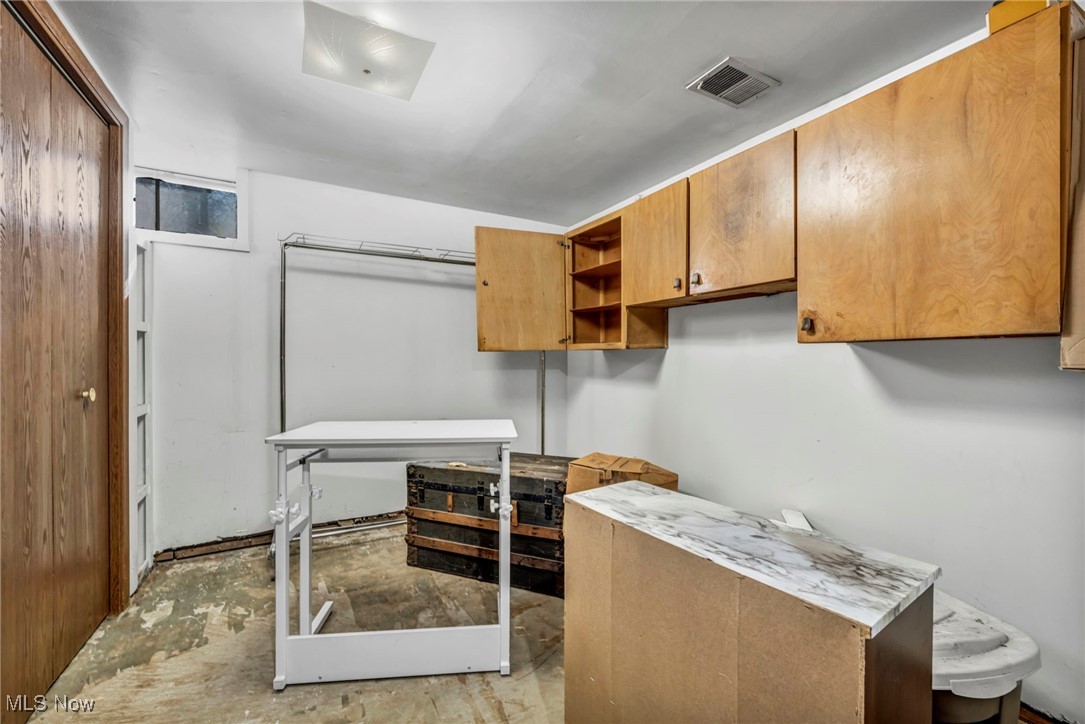 725 Neal Road, Unit 723 Akron, OH 44312 - Photo 33 of 47 Kitchen featuring brown cabinetry, unfinished concrete flooring, open shelves, and visible vents