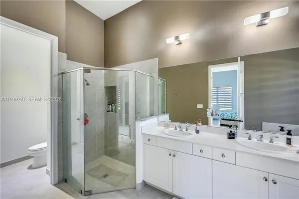 a bathroom with a double vanity sink toilet mirror and shower