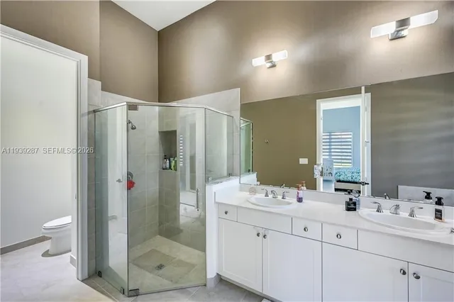 a bathroom with a double vanity sink toilet mirror and shower