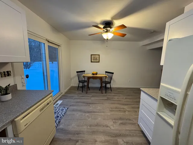 a living room with a dining table chairs and a refrigerator