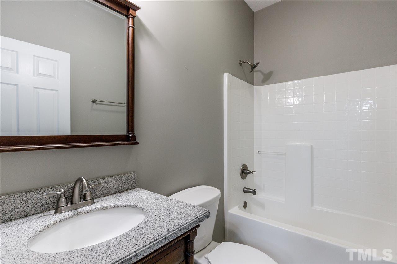 2921 Old Milburnie Road Raleigh, NC 27604 - Photo 22 of 27 a bathroom with a granite countertop sink a toilet and shower