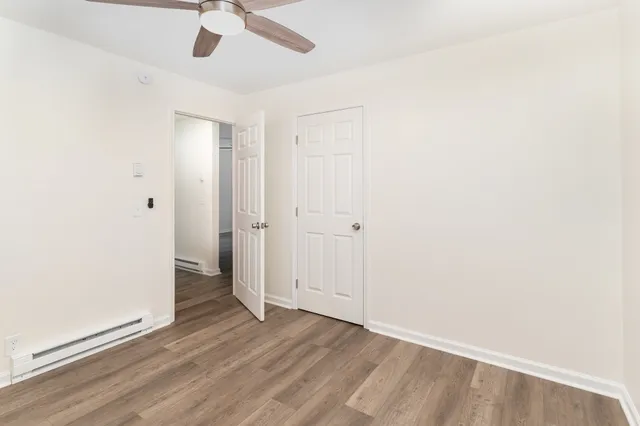 an empty room with wooden floor closet and windows