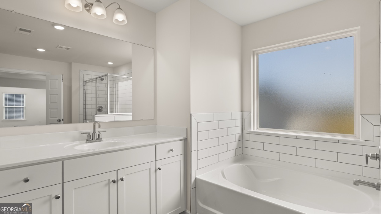 13604 Whitman Lane Covington, GA 30014 - Photo 15 of 52 a bathroom with a bathtub sink vanity and mirror