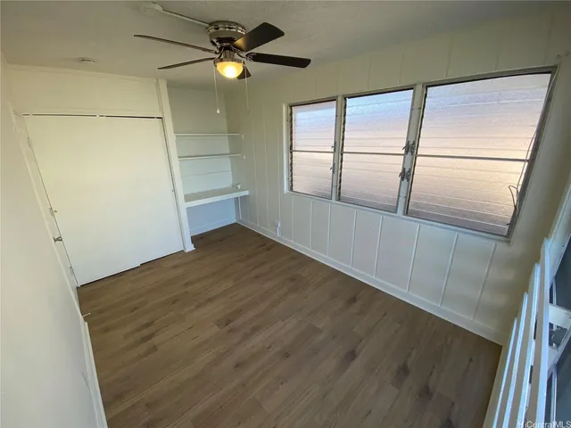a view of empty room with wooden floor and fan