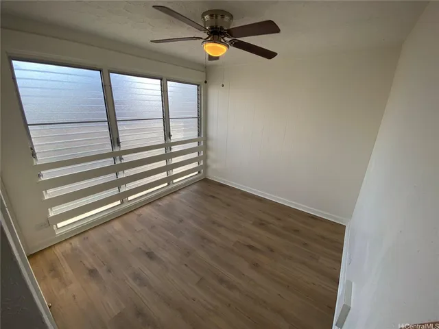 a view of empty room with wooden floor and fan