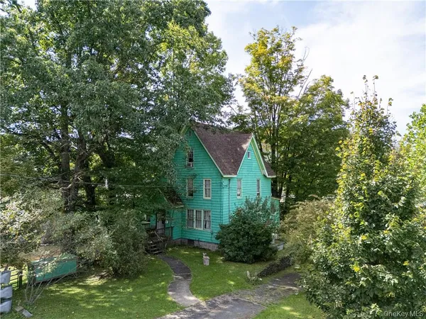 a view of house with yard and trees in the background