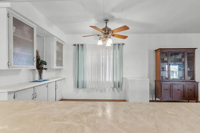 an empty room with chandelier fan and windows