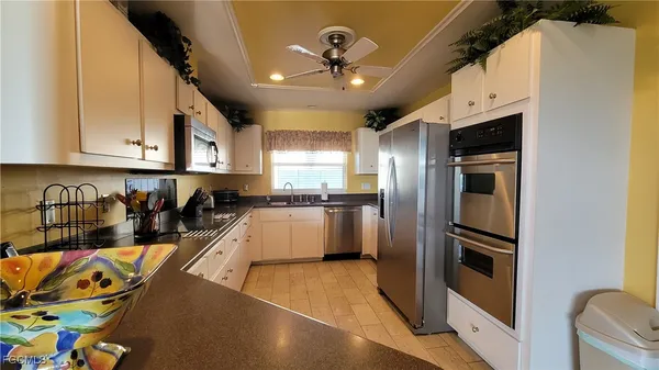 a kitchen with stainless steel appliances granite countertop a refrigerator a stove and a sink with wooden floor