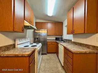 a kitchen with granite countertop a sink a stove and a refrigerator