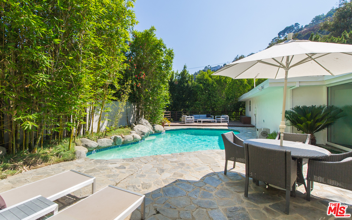 1908 North Beverly Drive Beverly Hills, CA 90210 - Photo 18 of 32 a view of a yard with a table and chairs under an umbrella