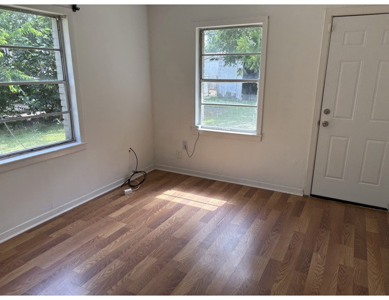 1213 8th Street Rosenberg, TX 77471 - Photo 3 of 7 an empty room with wooden floor and windows