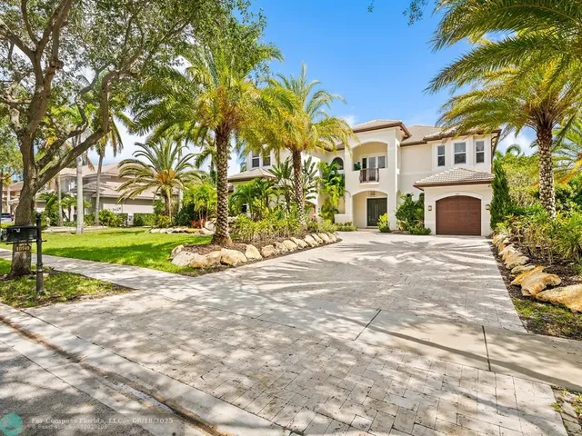 a view of a house with a small yard and large trees