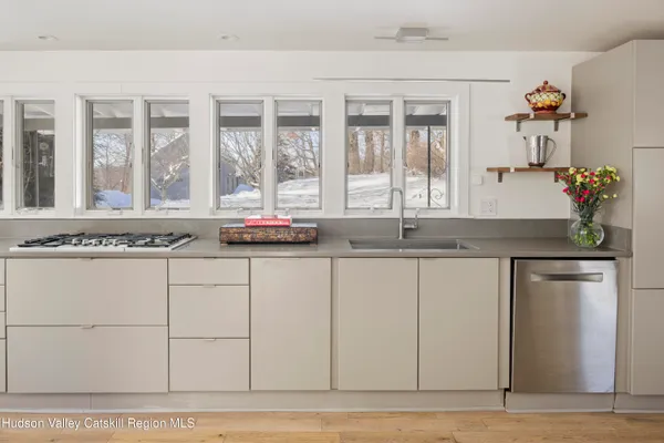 a kitchen with stainless steel appliances a sink dishwasher stove refrigerator and wooden floor
