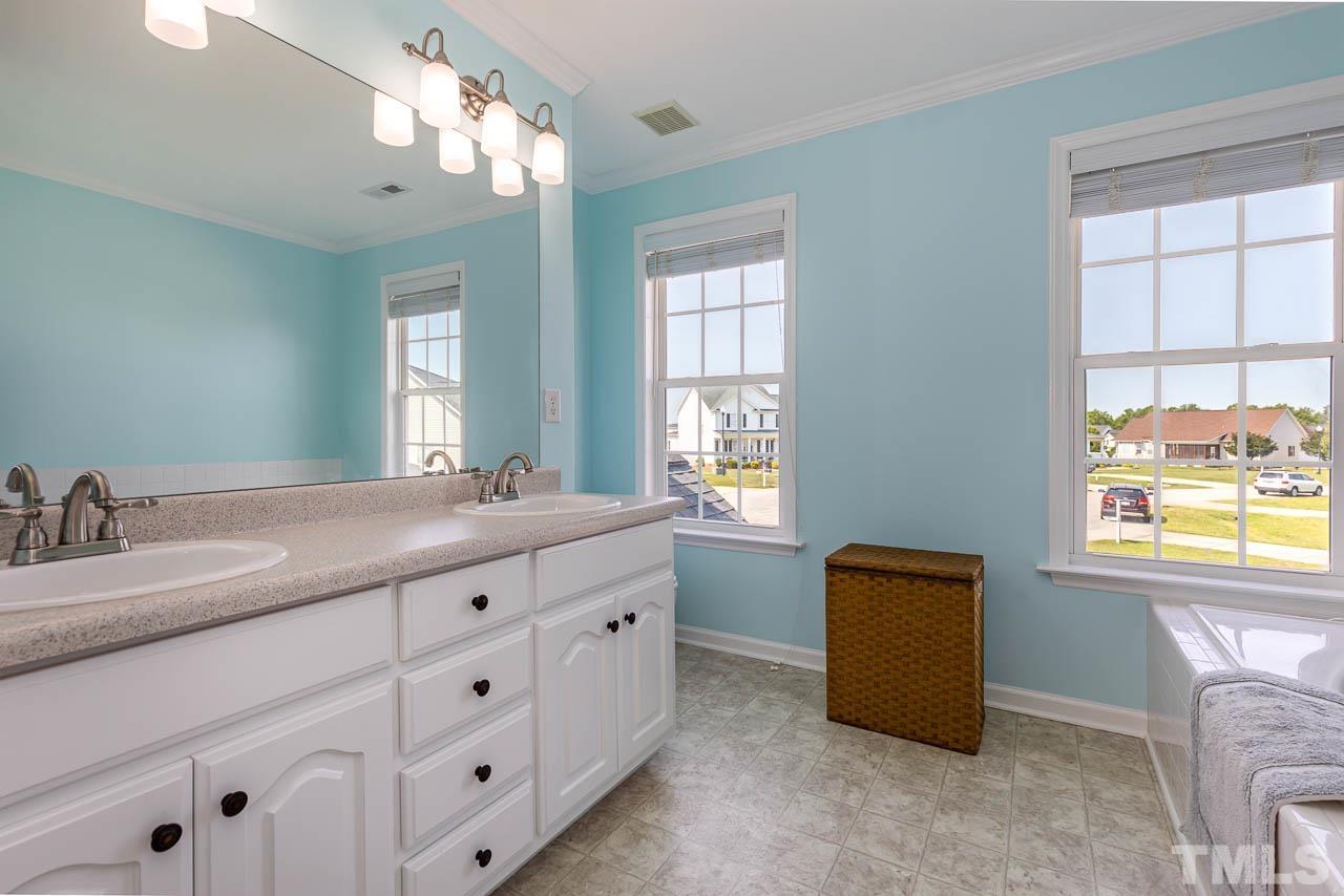 407 Ina Joe Place Willow Spring, NC 27592 - Photo 13 of 26 a bathroom with a granite countertop sink a mirror and a window
