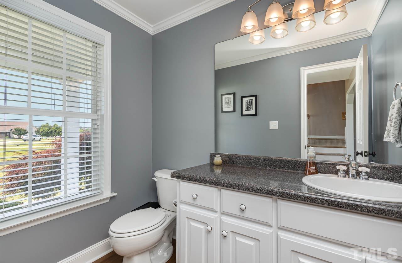 407 Ina Joe Place Willow Spring, NC 27592 - Photo 9 of 26 a bathroom with a granite countertop sink a toilet and a mirror