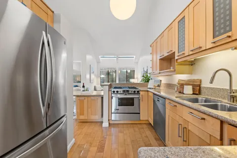 a kitchen with stainless steel appliances granite countertop a refrigerator a stove a sink and a microwave