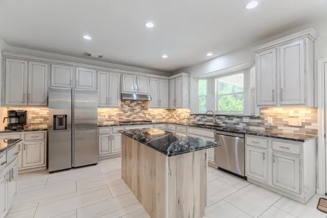 a kitchen with stainless steel appliances granite countertop a stove sink and cabinets