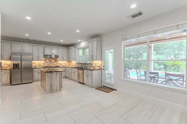 a kitchen with stainless steel appliances granite countertop a stove top oven a sink dishwasher and a refrigerator