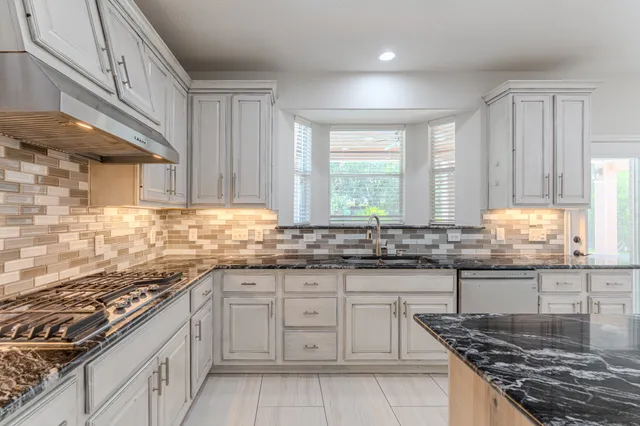 a kitchen with granite countertop a sink stove and cabinets