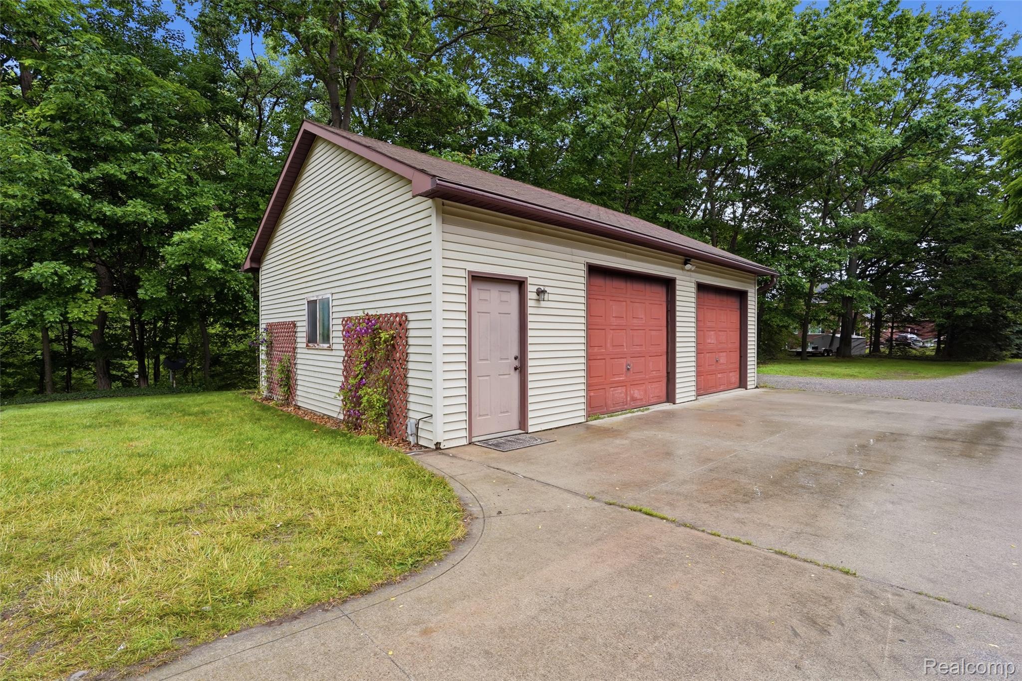 68345 Romeo Plank Road Ray, MI 48096 - Photo 10 of 52 Detached three-car garage featuring a tan siding exterior, red garage doors, a side entry door, and a small window