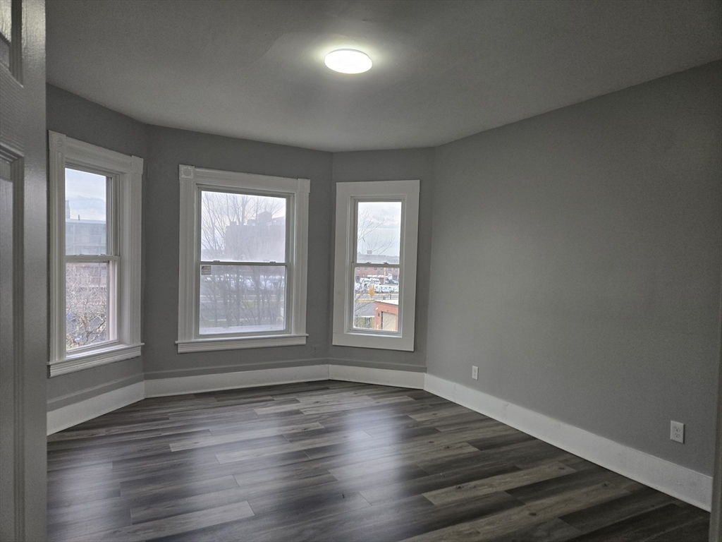 123 Walnut Street, Unit 4L Holyoke, MA 01040 - Photo 4 of 16 an empty room with wooden floor and windows