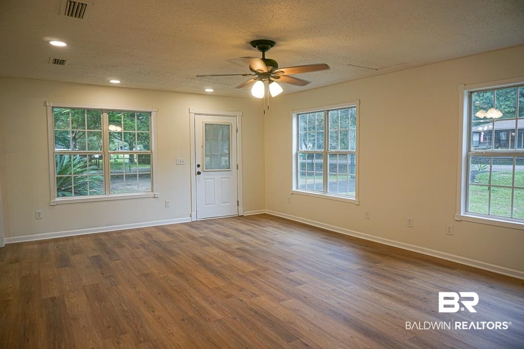 4734 Kirkwell Drive Mobile, AL 36619 - Photo 5 of 18 Unfurnished room featuring a textured ceiling, ceiling fan, and hardwood / wood-style floors
