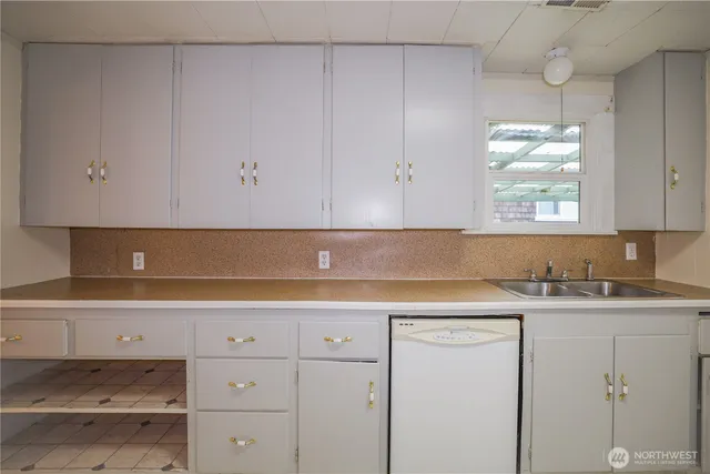 a kitchen with white cabinets and sink