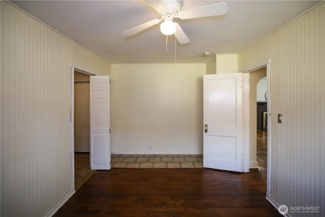 an empty room with wooden floor closet and chandelier fan
